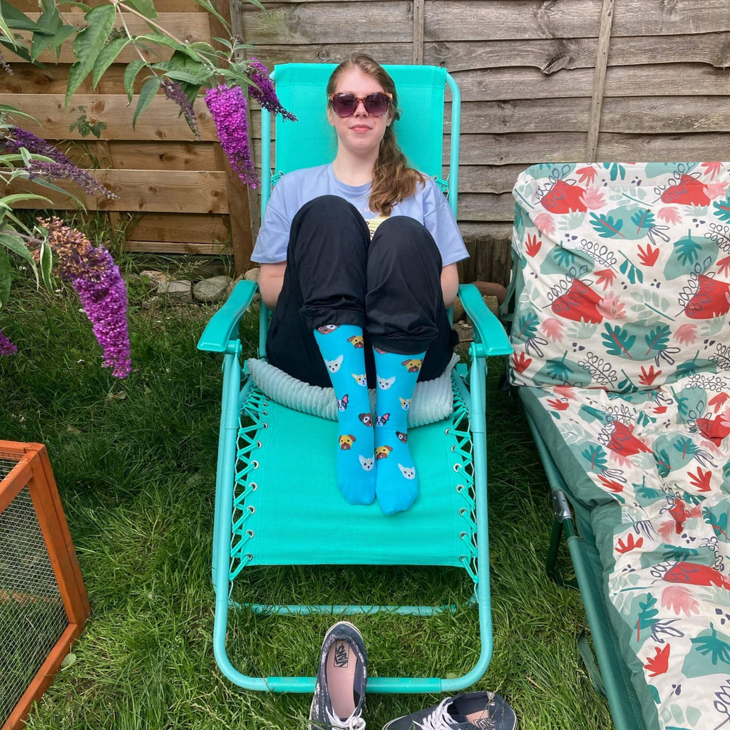 Woman sitting in chair wearing Teal knee high compression socks with dog pattern