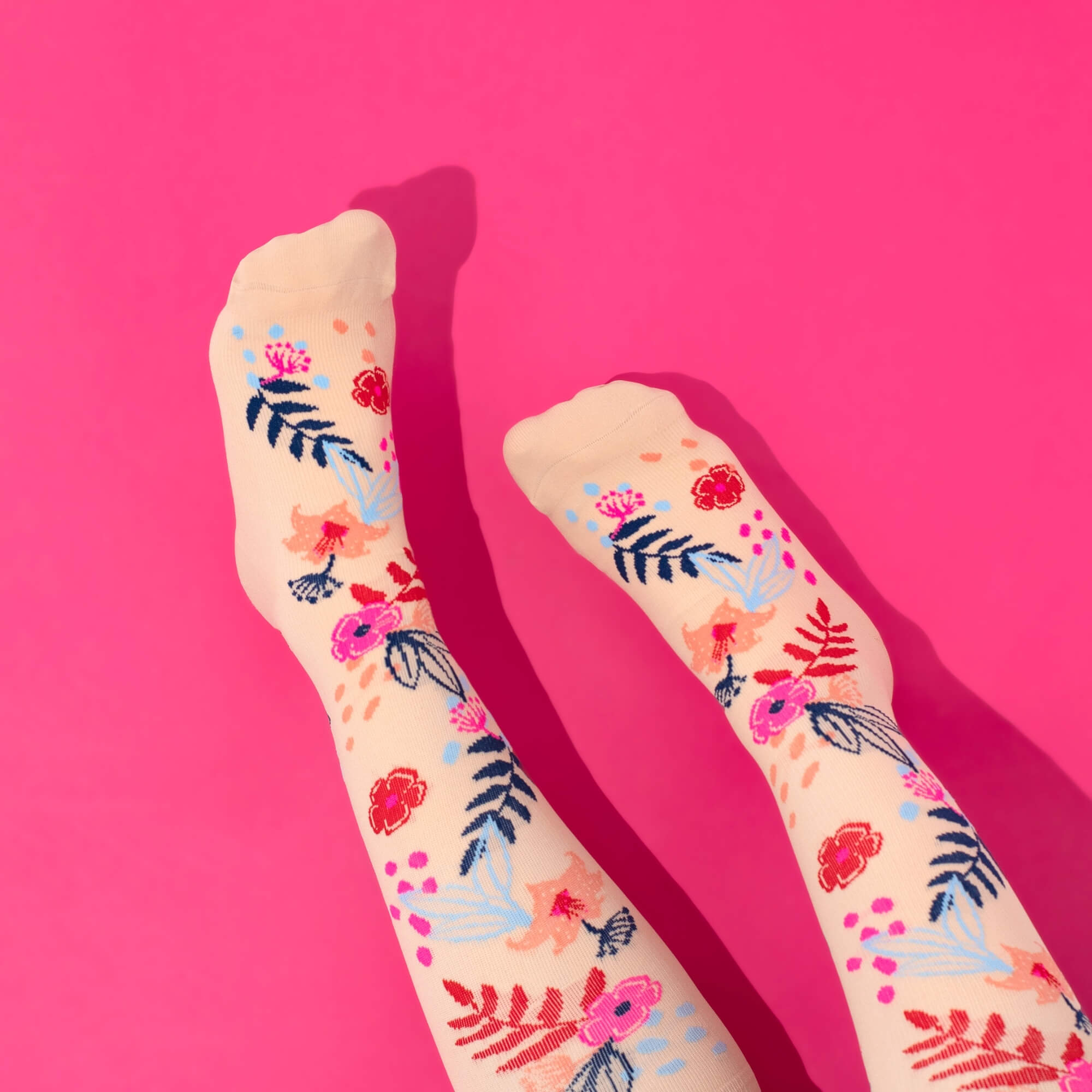 Floral-patterned compression socks on a pink background