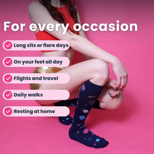 Model kneeling in navy blue knee high compression socks with space-themed design